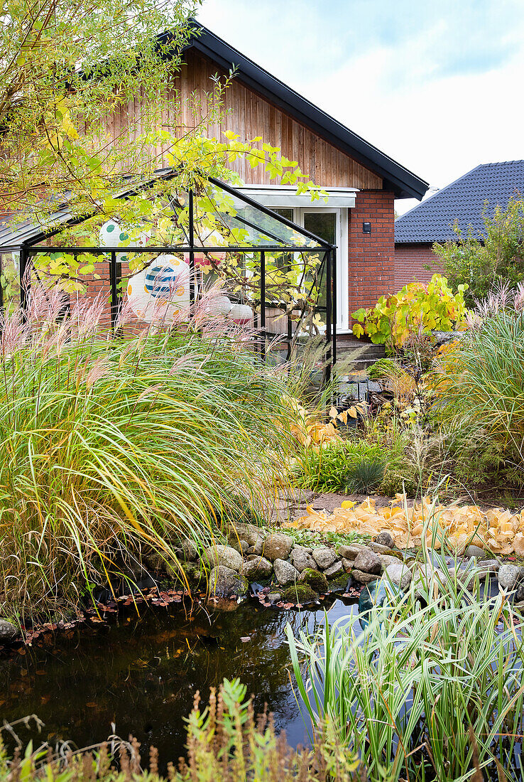 Autumnal atmosphere in the garden with greenhouse and pond