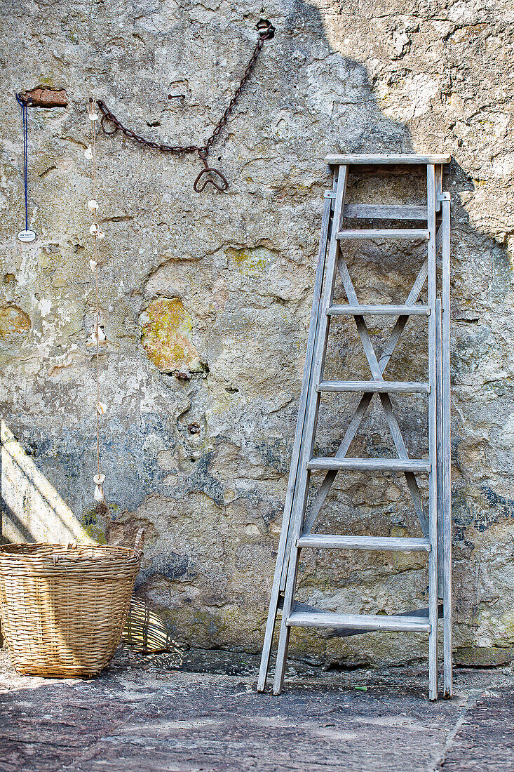 Old wooden ladder and basket on a dilapidated stone wall