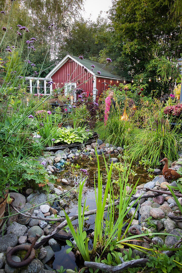 Sommerliche Gartenidylle mit Teich und rotem Gartenhaus