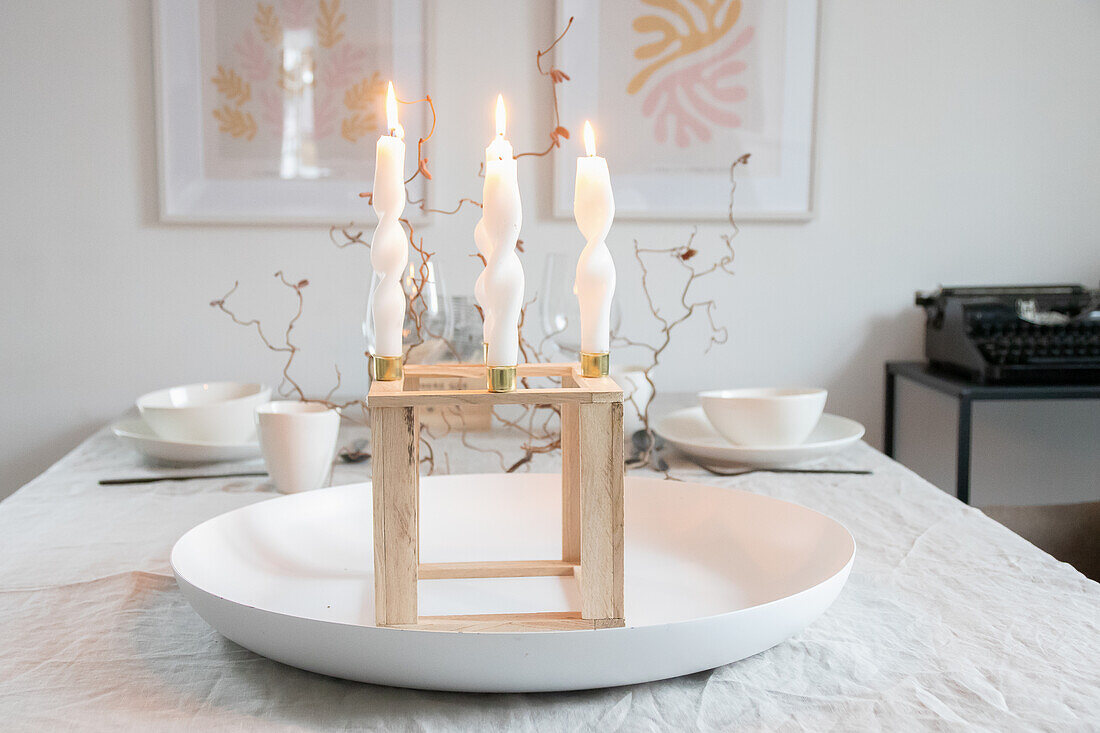 Wooden candle holder with twisted candles on table with white crockery