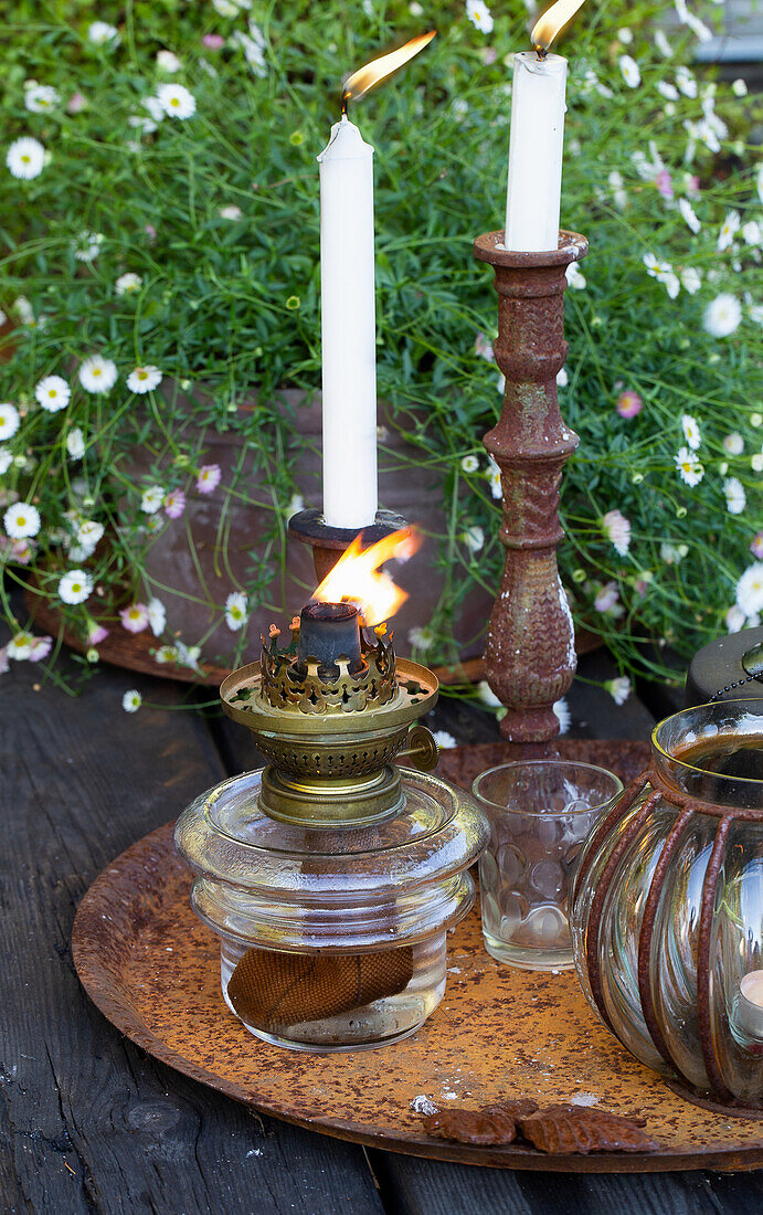 Antikes Windlicht und Kerzenhalter auf rustikalem Holztisch im Garten