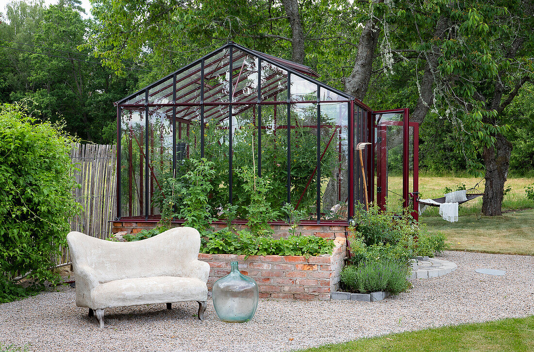 Greenhouse in the garden with raised bed and cosy outdoor area