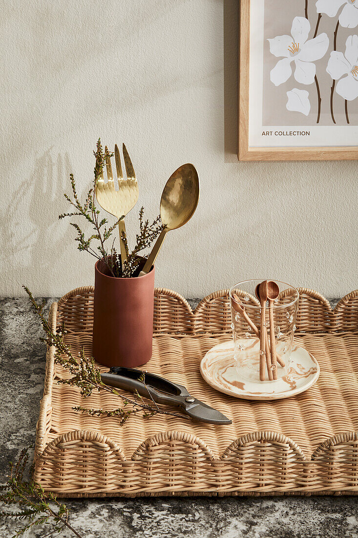 Rattan tray with gold-coloured cutlery and ceramic crockery