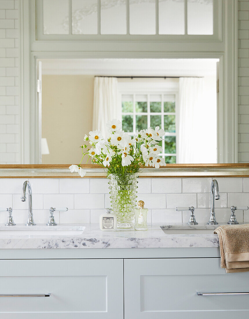 Marble washbasin with double washbasin and decorative glass vase with white flowers