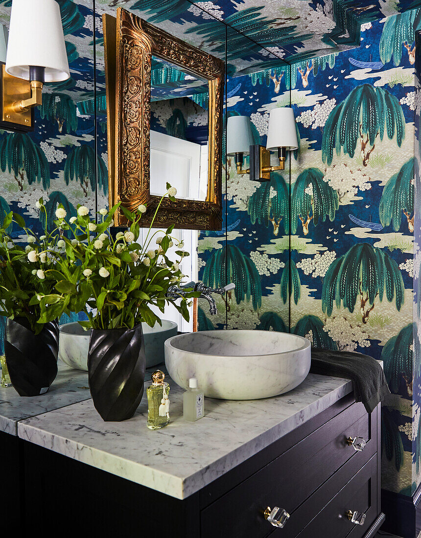 Bathroom corner with marble washbasin and wallpaper with nature motif