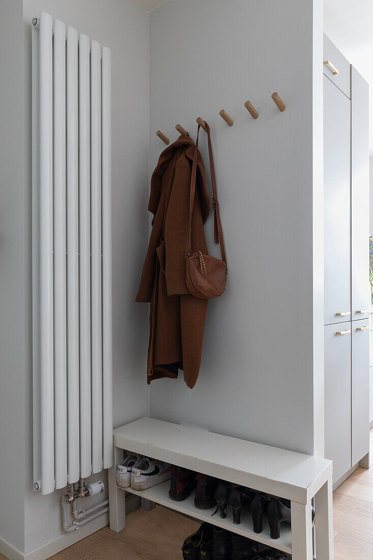 Entrance area with coat hooks and white bench with shoe rack