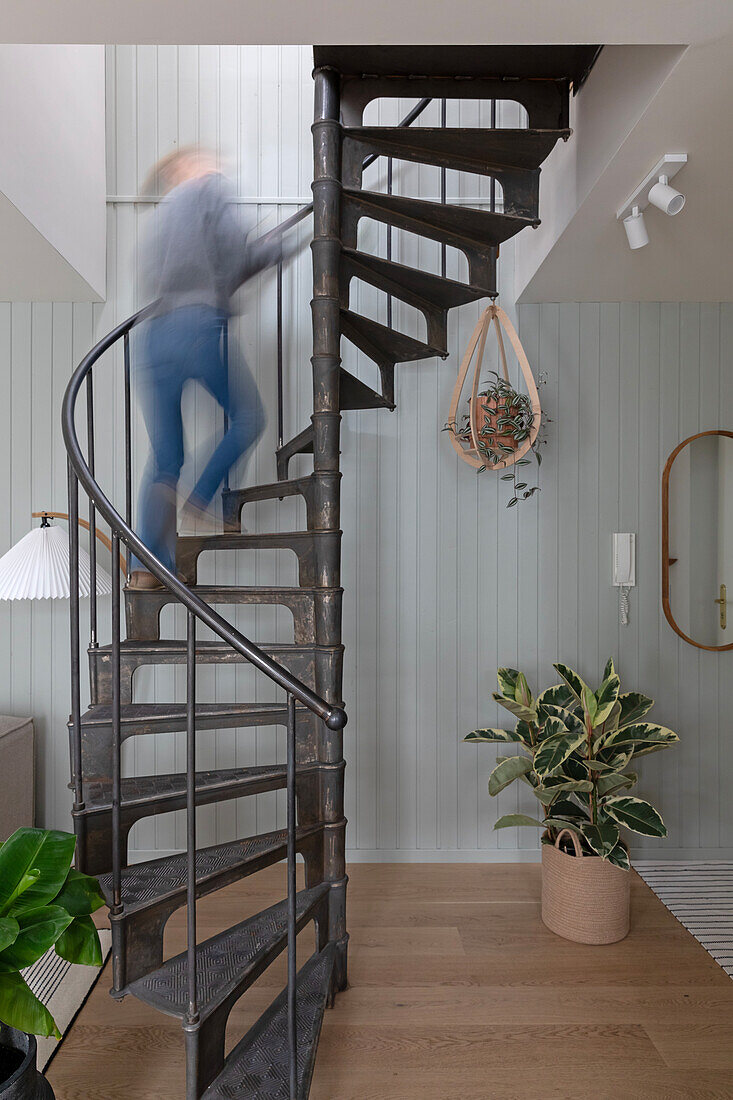 Moderne Wendeltreppe aus Metall vor holzvertäfelter Wand