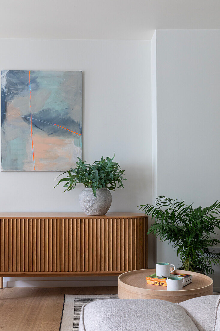 Modern living area with wooden sideboard, artwork and green plants