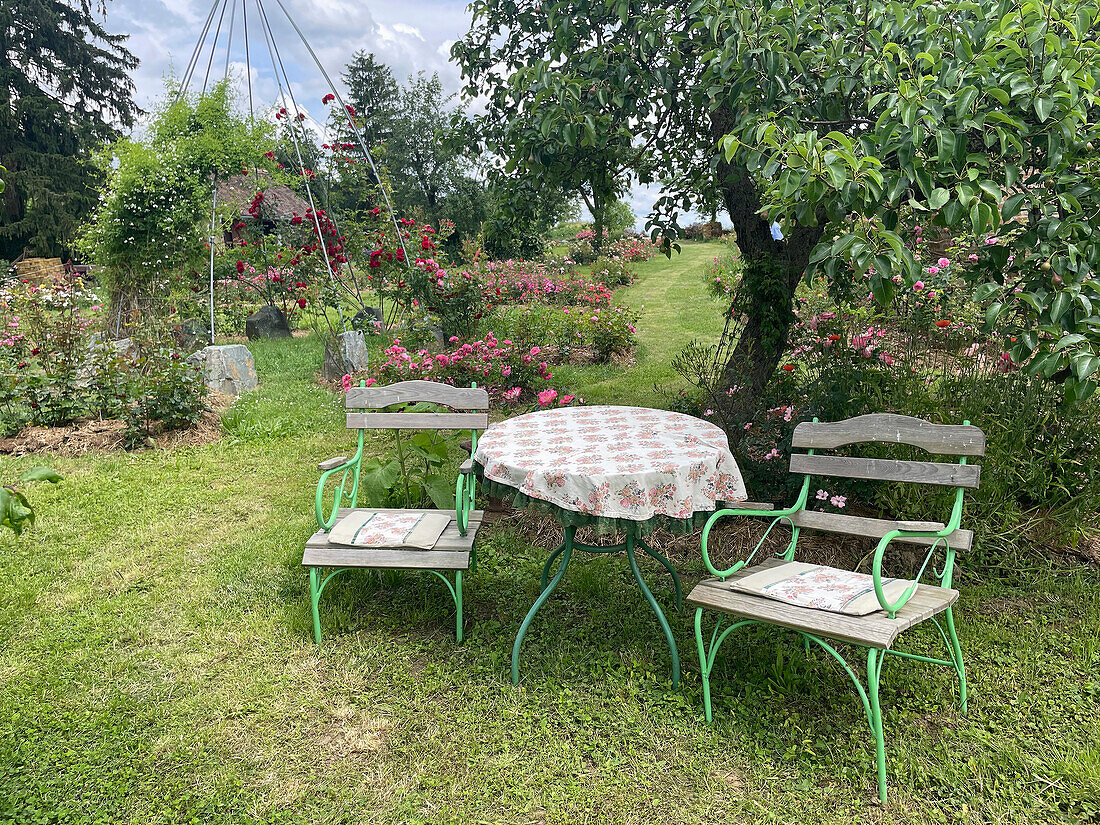 Sitzplatz aus rundem Tisch und zwei Stühlen im Rosengarten