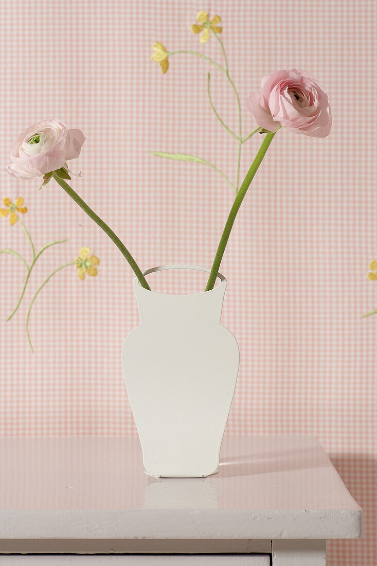 DIY-Vase mit zwei rosa Ranunkeln auf Holztisch