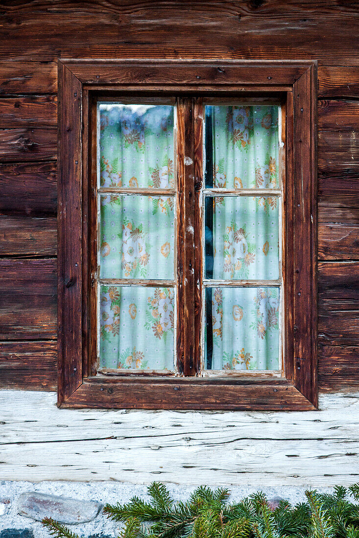 Window with patterned curtains in wooden house