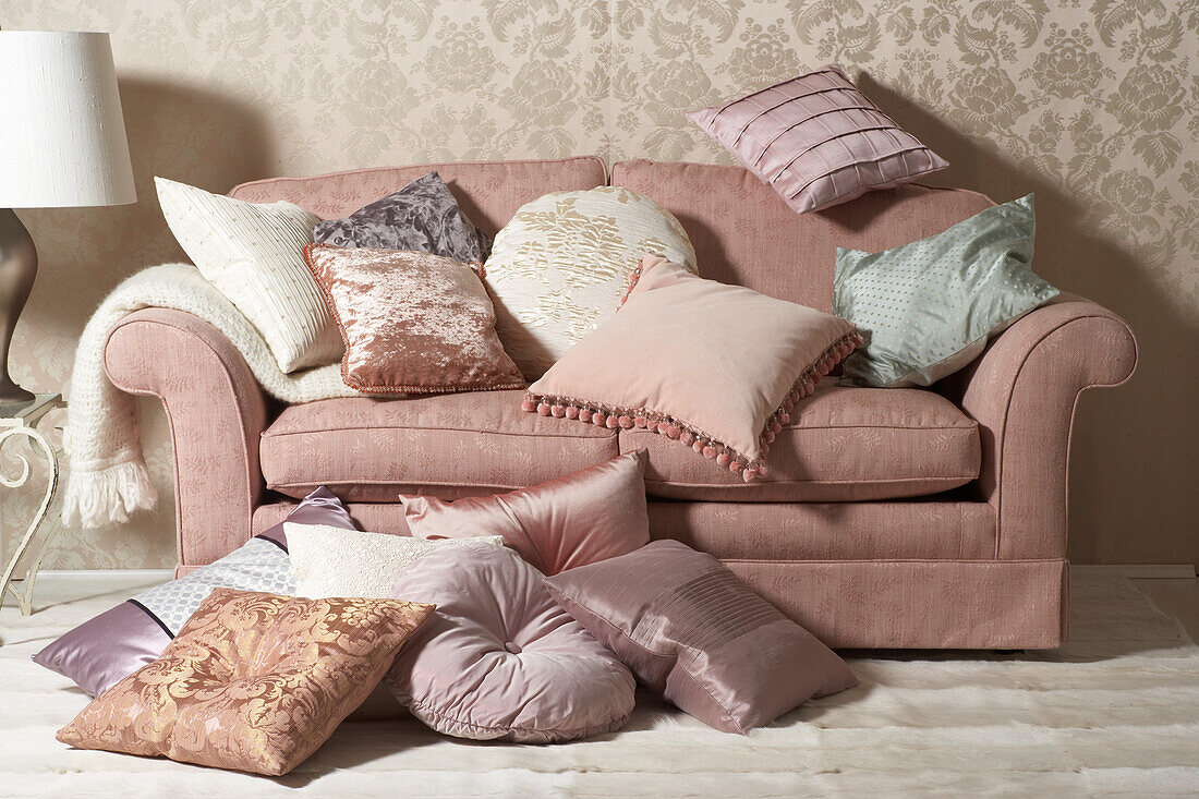 Pink sofa with lots of throw pillows in various pastel colors