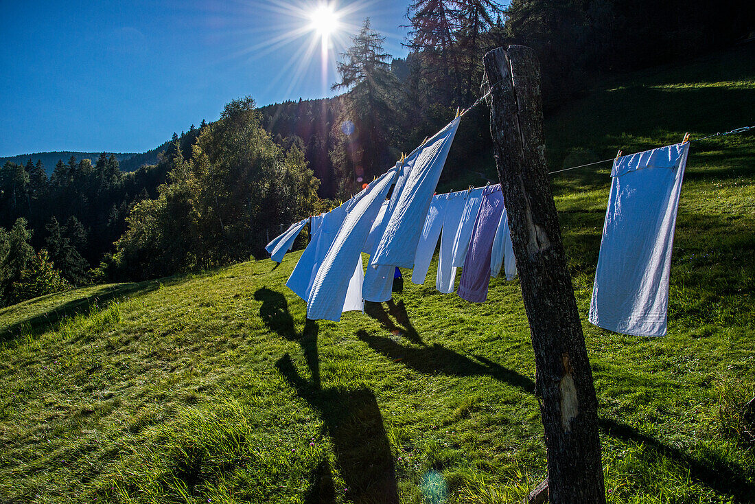 Wäscheleine mit Handtüchern auf einer sonnigen Wiese im Bergland