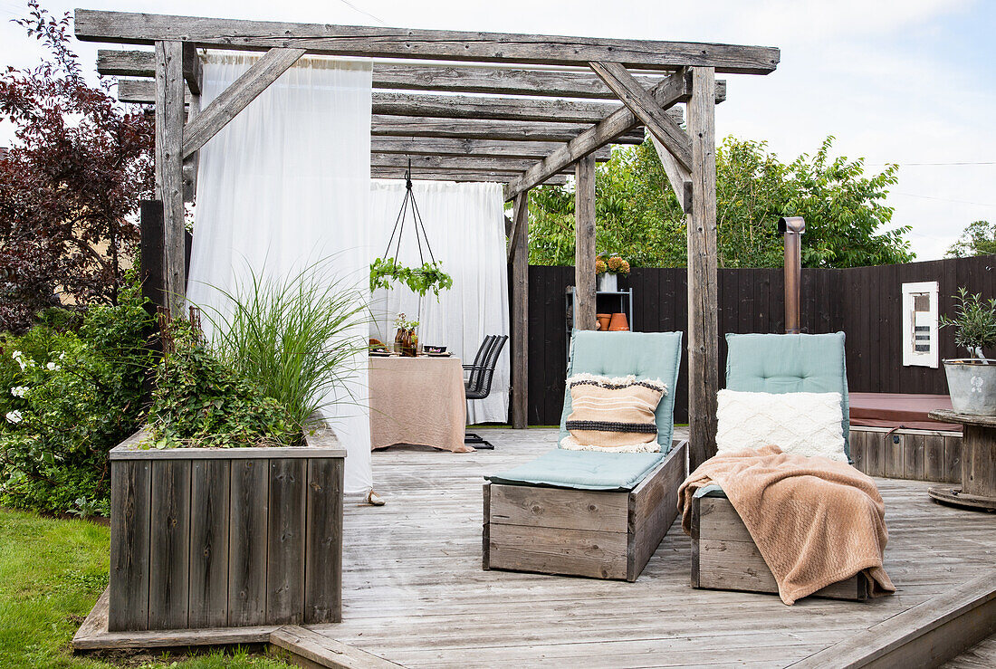 Wooden terrace with pergola, deckchairs and dining area