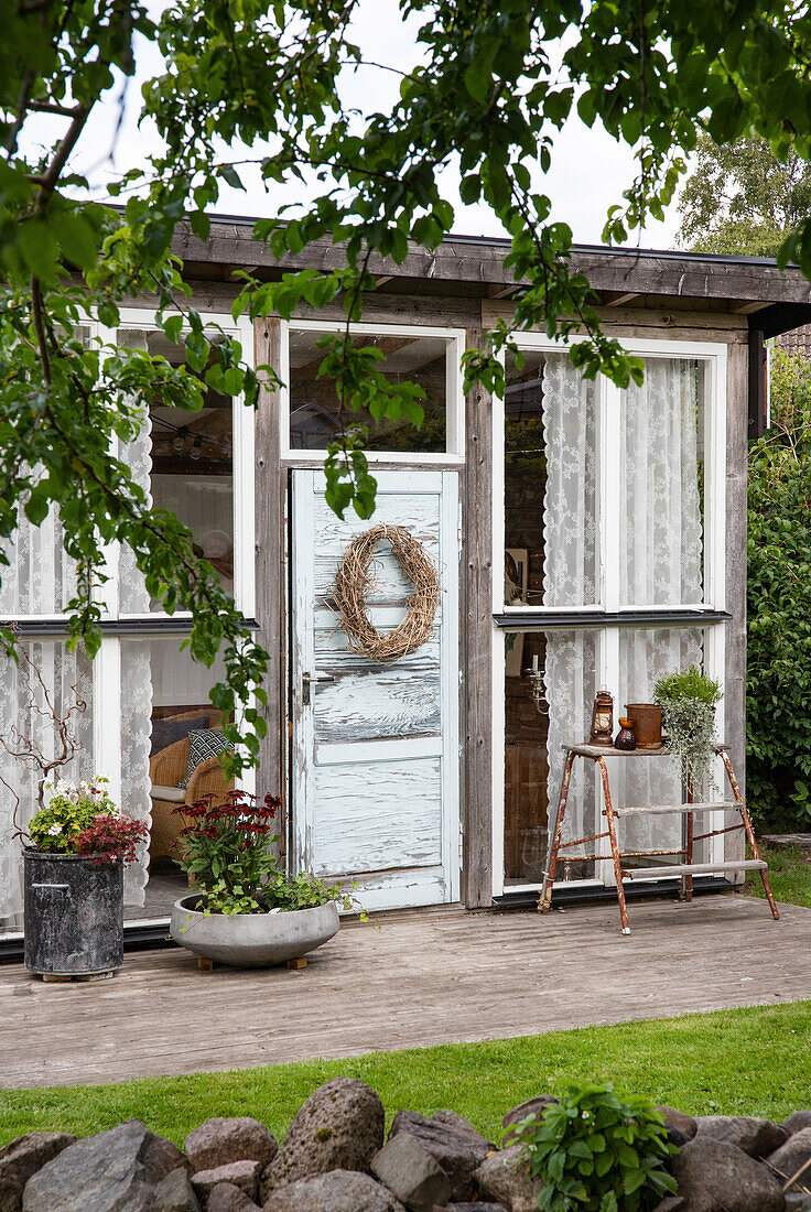 Gemütliches Gartenhaus mit dekoriertem Eingang und Pflanzen