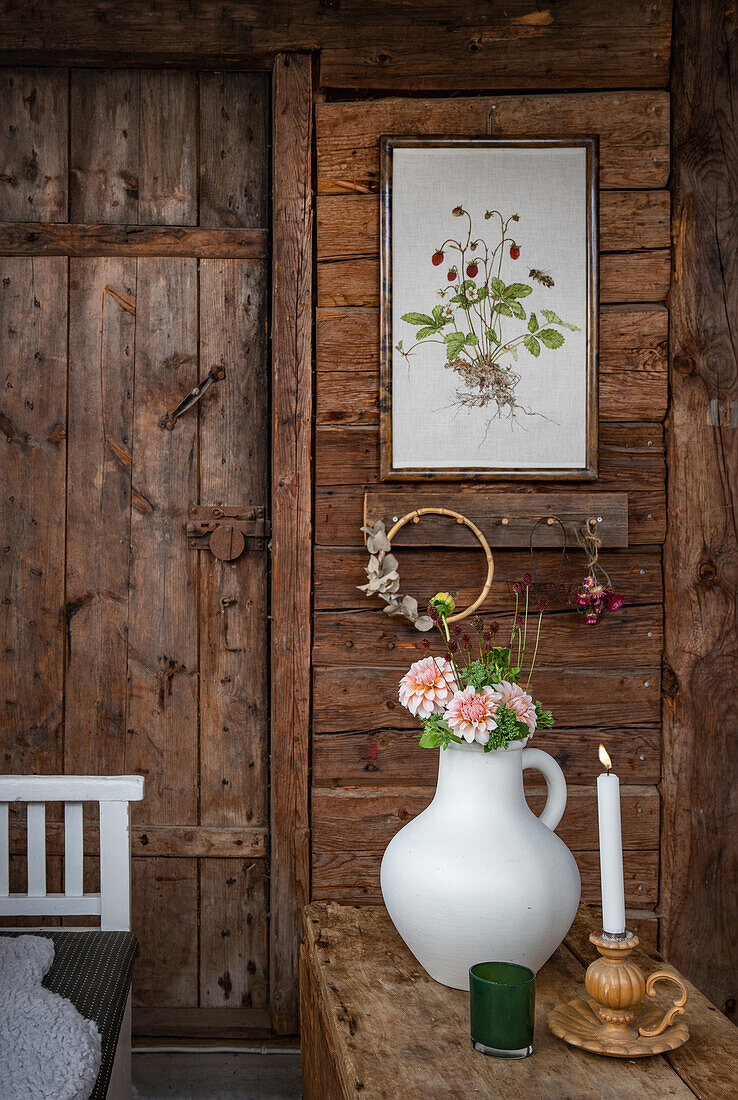 Rustikale Holzwand mit Blumenbild, Kerze und Blumenvase