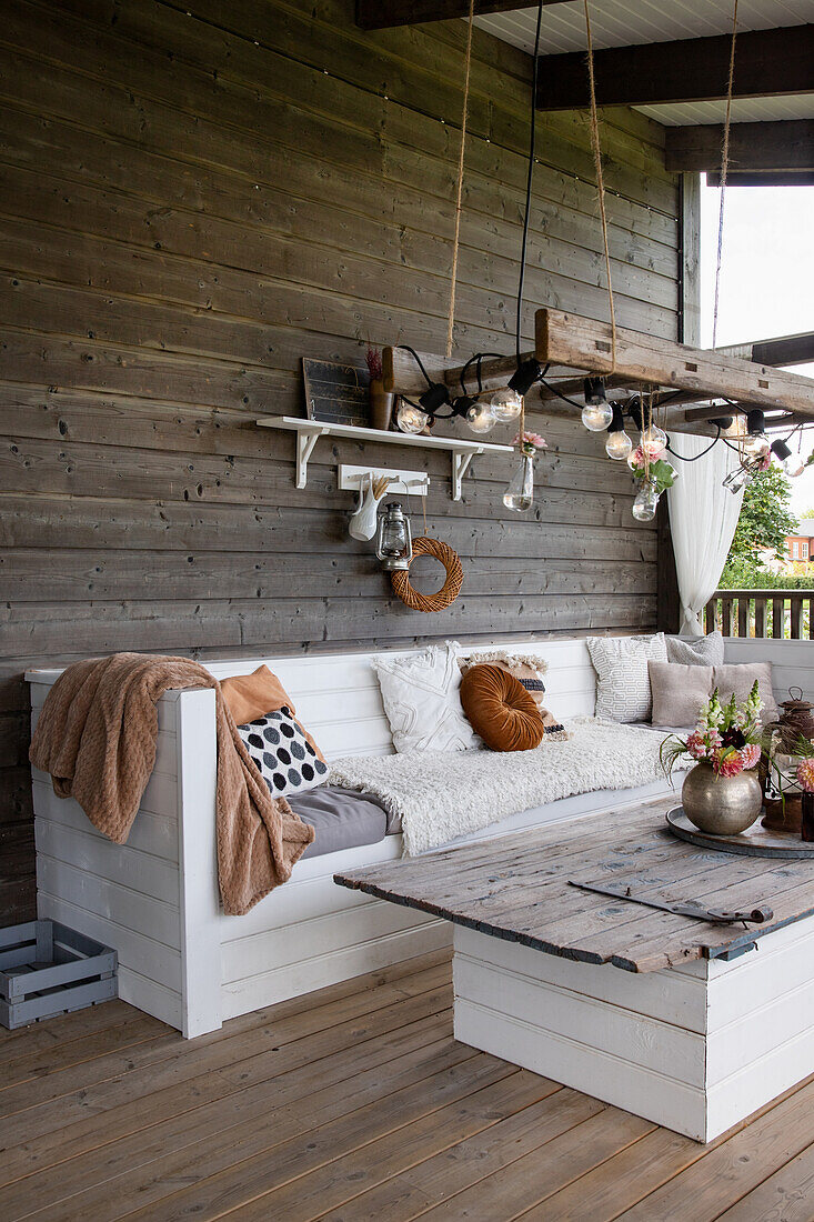 Holzterrasse mit Sitzbank, selbstgemachtem Tisch und Lichterkette