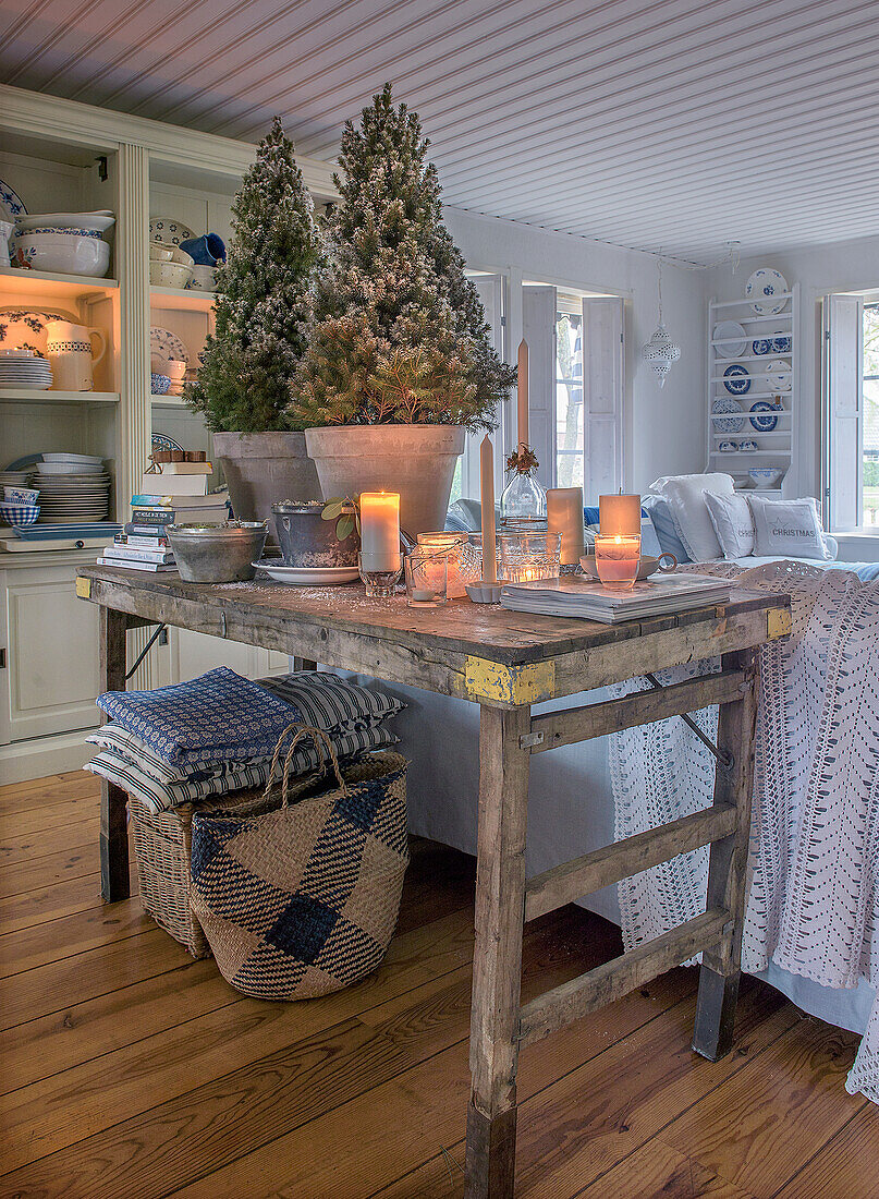 Rustic wooden table with candles, books and fir trees in the living room