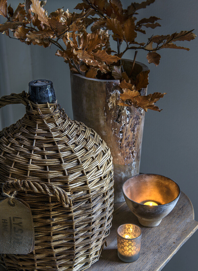 Autumnal decoration with vintage demijohn, dried branches and candlelight