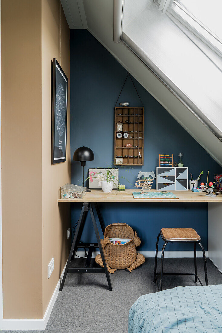 Desk under a sloping roof, blue-painted wall with a box