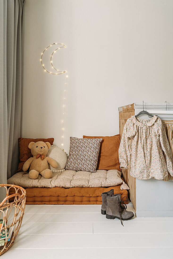 Gemütliche Kinderzimmer-Ecke mit Kissen und Lichterkette in Mondform