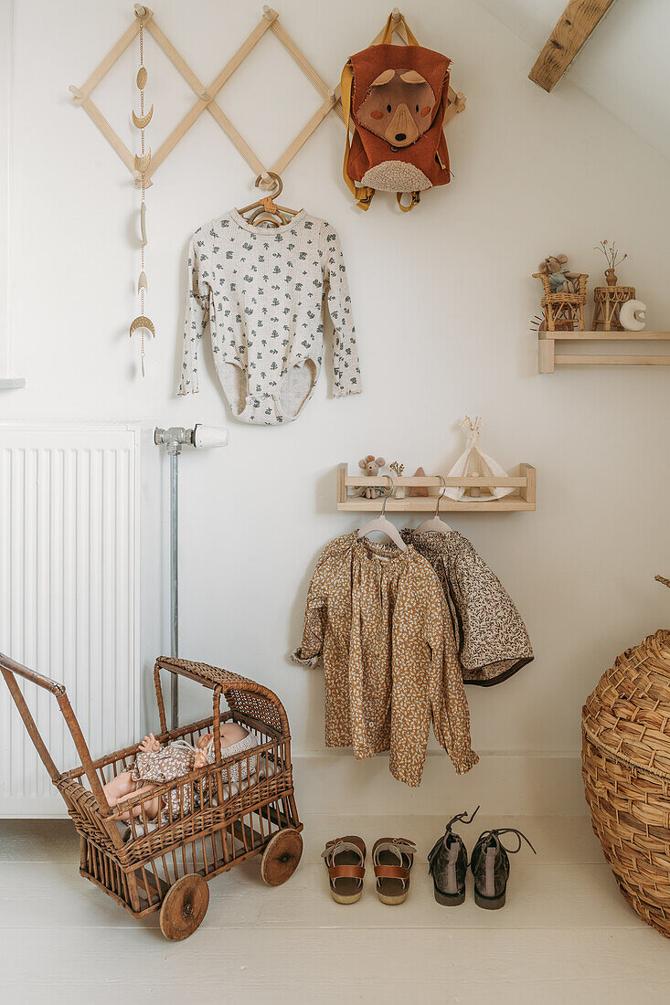 Wand eines Kinderzimmers mit Garderobe, Regalen und Kleidung