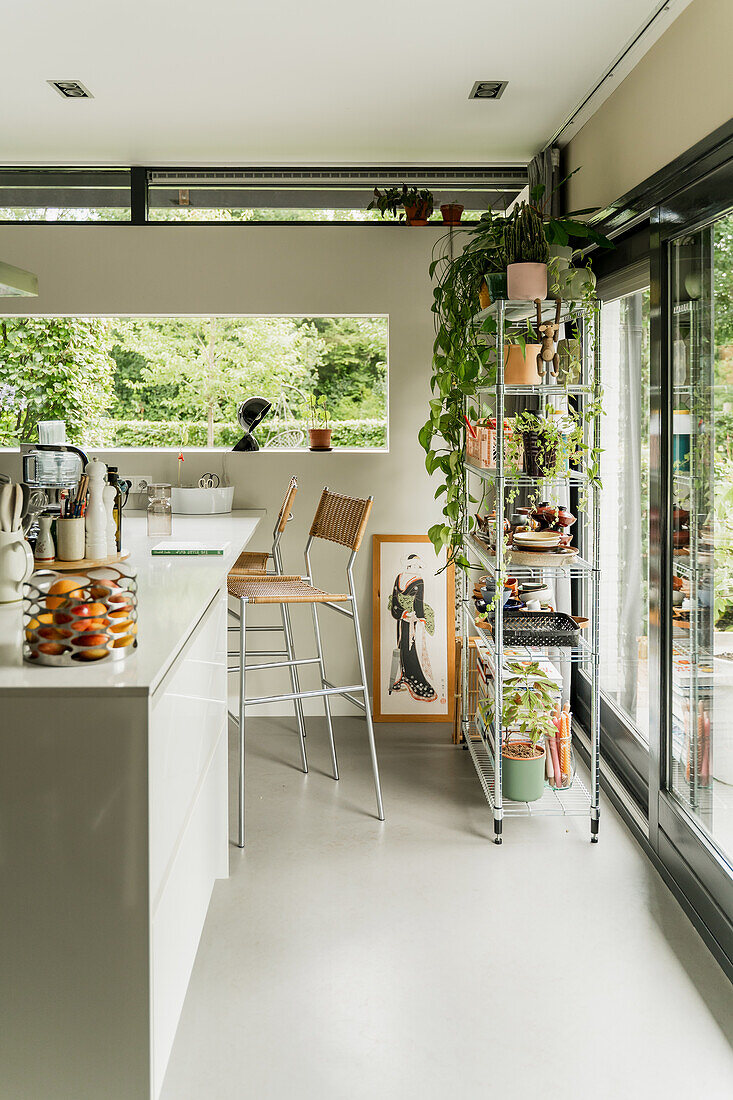 Modern kitchen with bar stools and plant shelf by the patio door