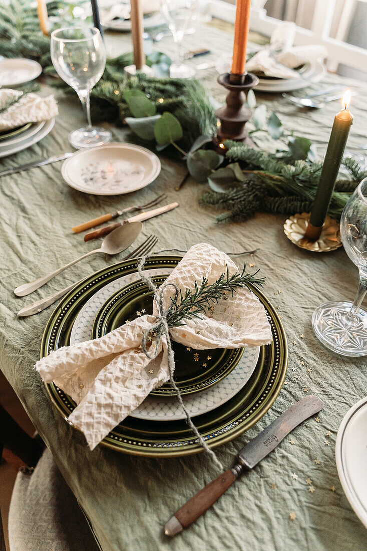 Festive table setting with green tablecloth, Christmas decorations and candles