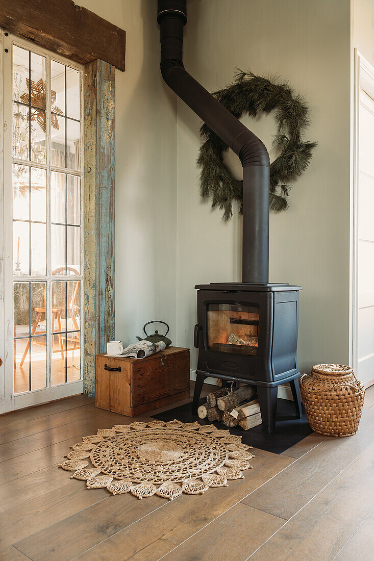 Small wood-burning stove with wood storage and natural fibre rug on wooden floor