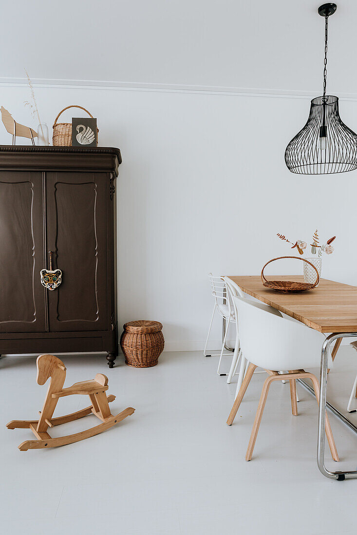 Dining area with wooden table, white chairs and black hanging lamp