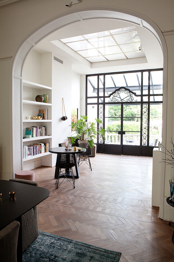 Open-plan living room with parquet floor, round arch and view of the veranda