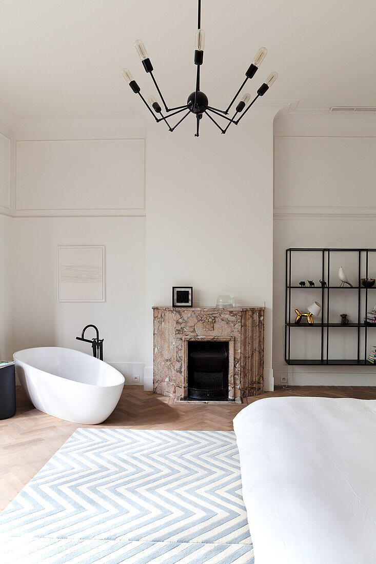 Modern bedroom with freestanding bathtub and marble fireplace