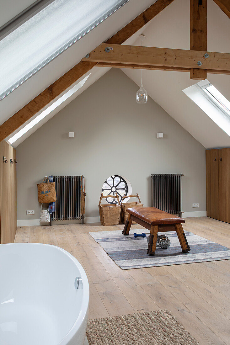 Bright attic bathroom with free-standing bathtub and wooden beams