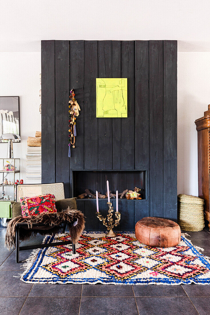 Black fireplace, colorful carpet and candlesticks in the living room