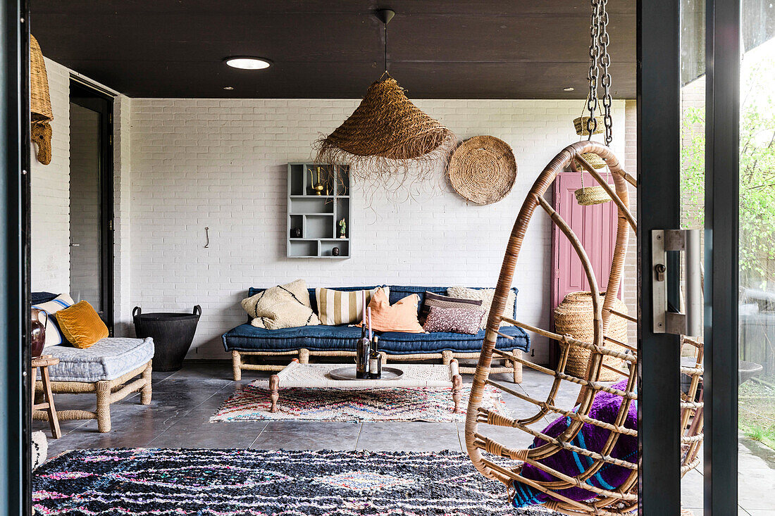 Covered terrace with hanging chair, outdoor furniture and throw rugs