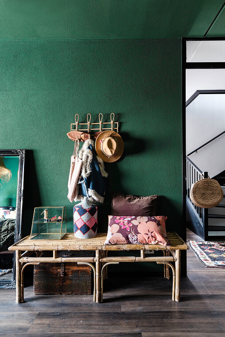 Room with wooden bench, green-painted wall and colorful pillows