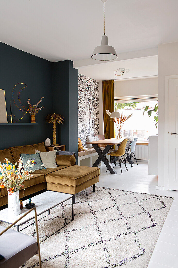 Living room with velvet sofa, dark blue wall and patterned carpet