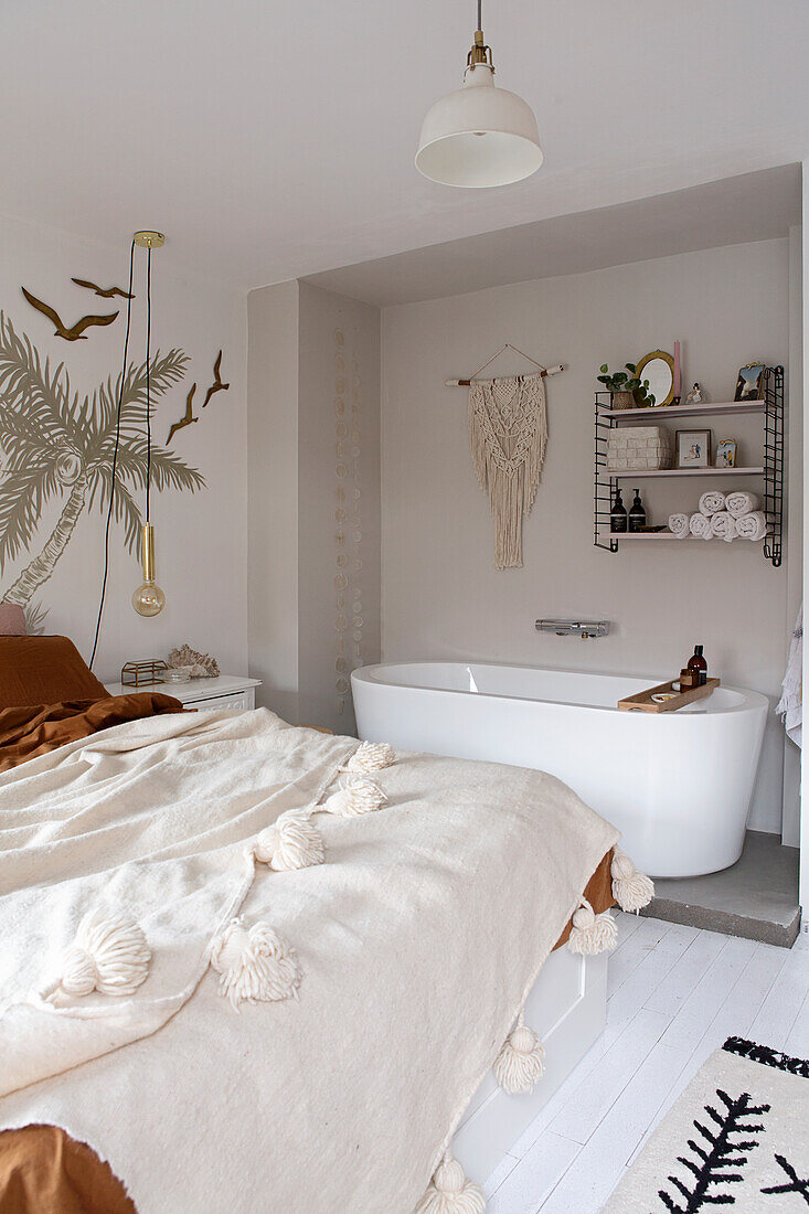 Schlafzimmer mit freistehender Badewanne und Makramee an der Wand