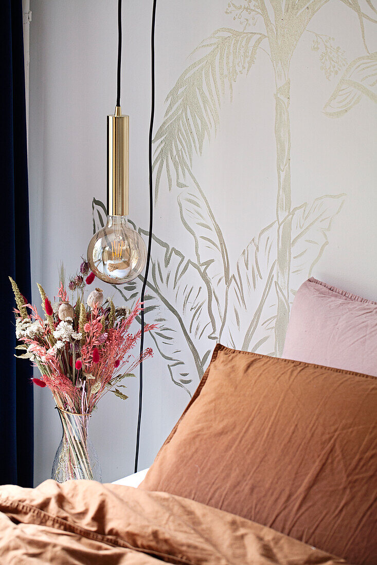 Bedroom with bouquet of dried flowers and wallpaper with plant motif