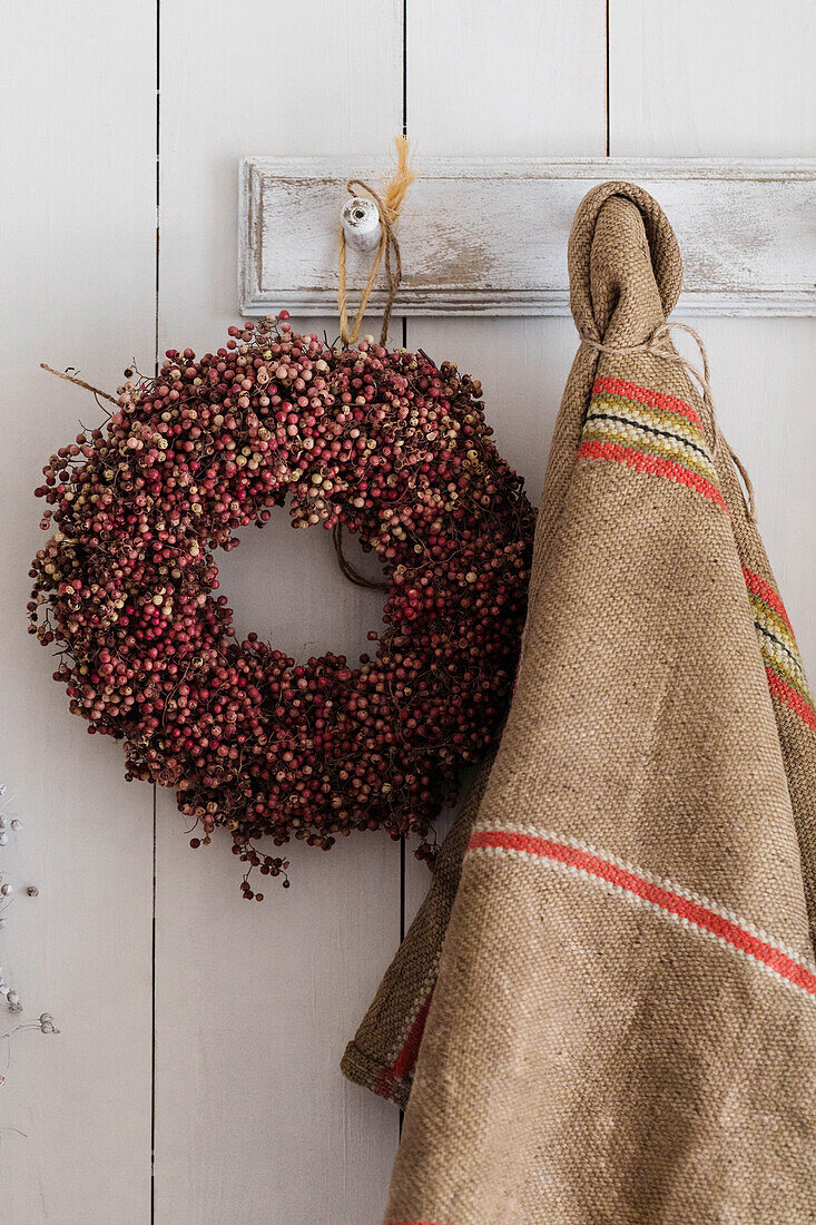 Wreaths of pink pepper berries and jute sack on coat rack, shabby chic