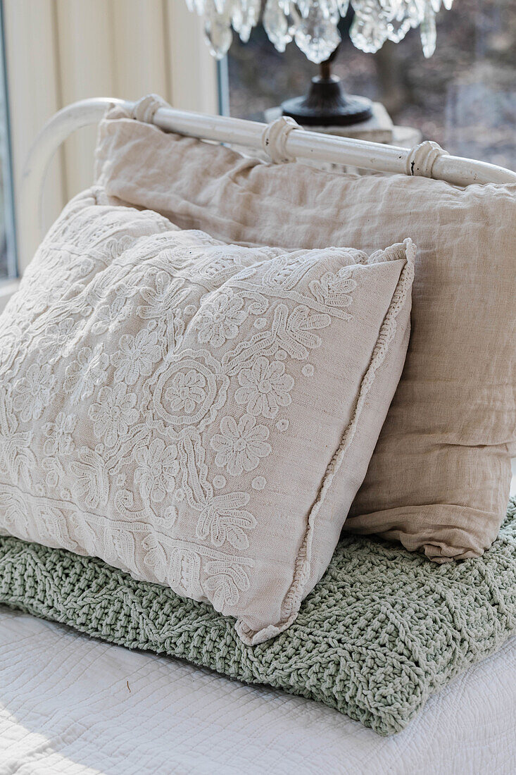 Stacked cushions with floral embroidery on a green knitted blanket