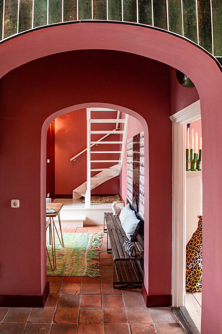 Living area with pink walls, green tiles and spiral staircase