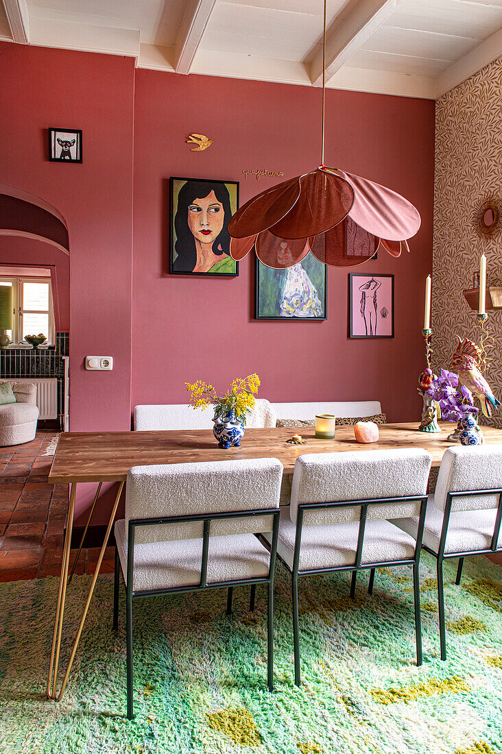 Dining area with wooden table, modern chairs and wall in pink