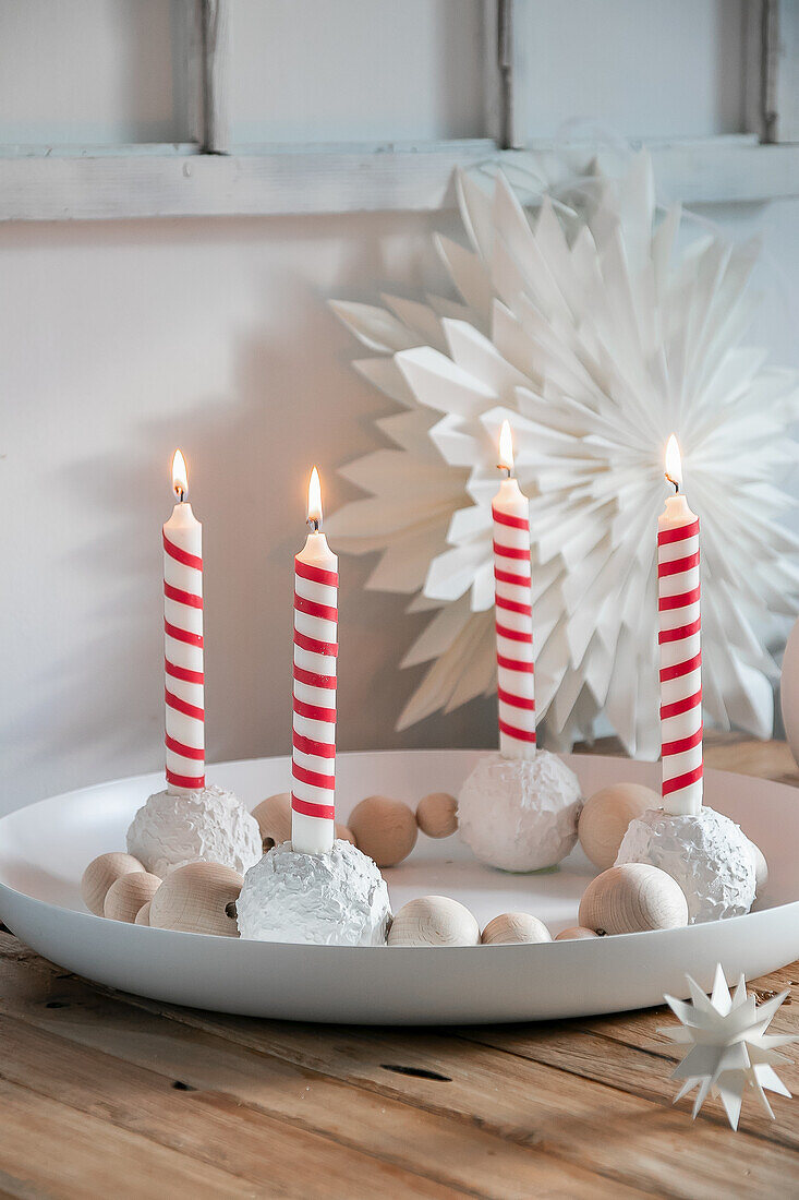 Advent wreath with red and white striped candles and wooden baubles