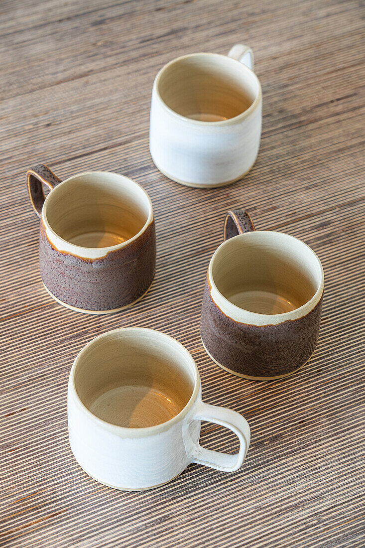 Four handmade ceramic cups on a wooden table