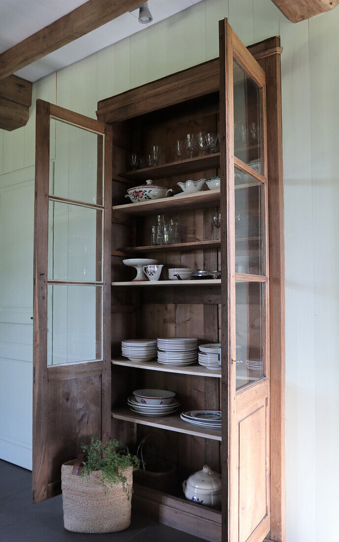 Vitrine aus Holz mit Geschirr und Gläsern im Landhausstil