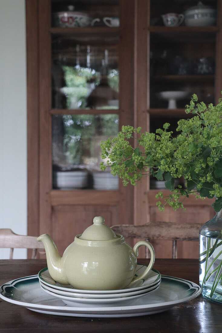 Ceramic teapot on a stack of plates, bouquet of flowers