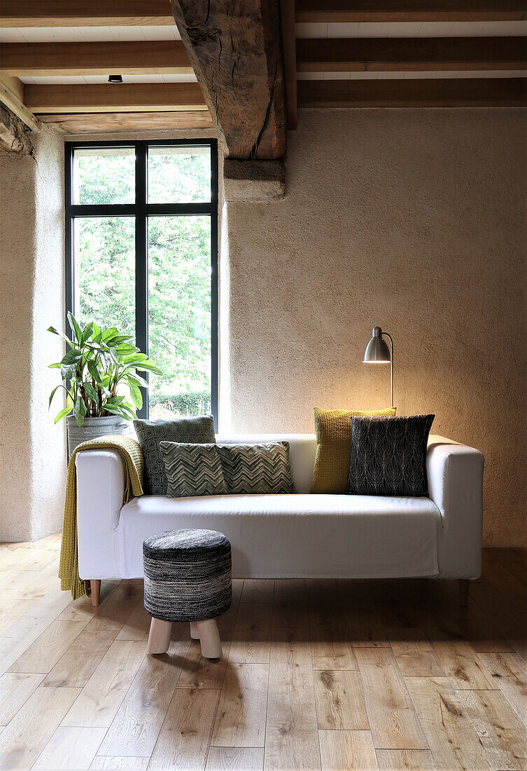 White sofa with patterned cushions in living room with wooden beamed ceiling