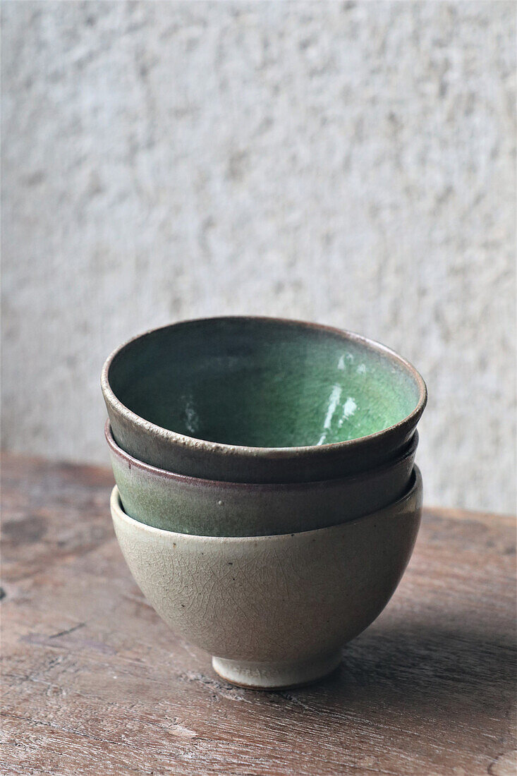 Three handmade ceramic bowls on wooden table