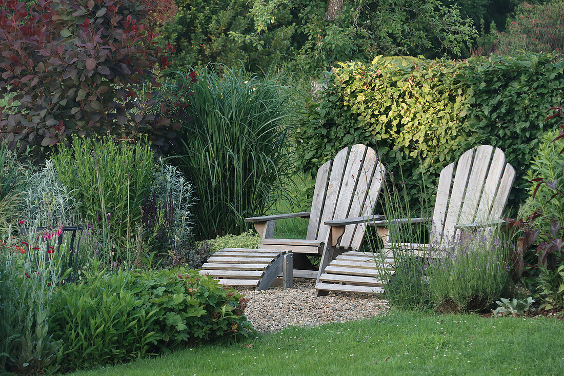 Two wooden deckchairs in the green garden